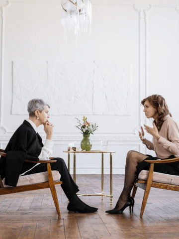 Two women sitting in chairs and having a cnversation.